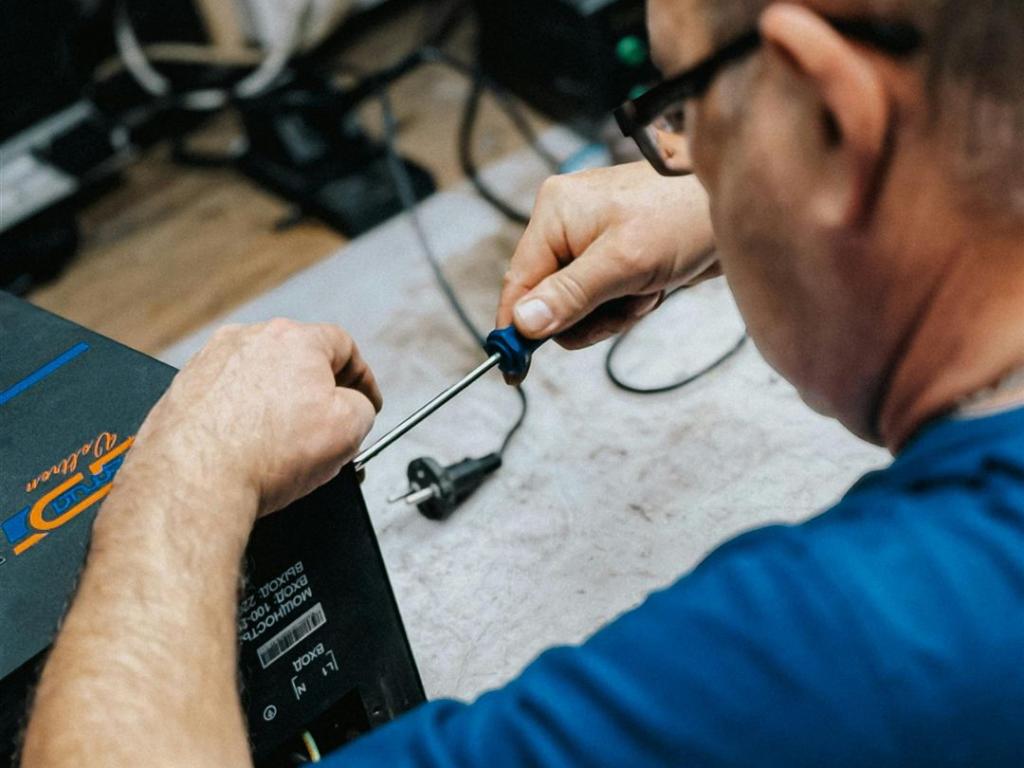 Ein qualifizierter Techniker, der in einer Werkstattumgebung an elektronischen Reparaturaufgaben arbeitet.